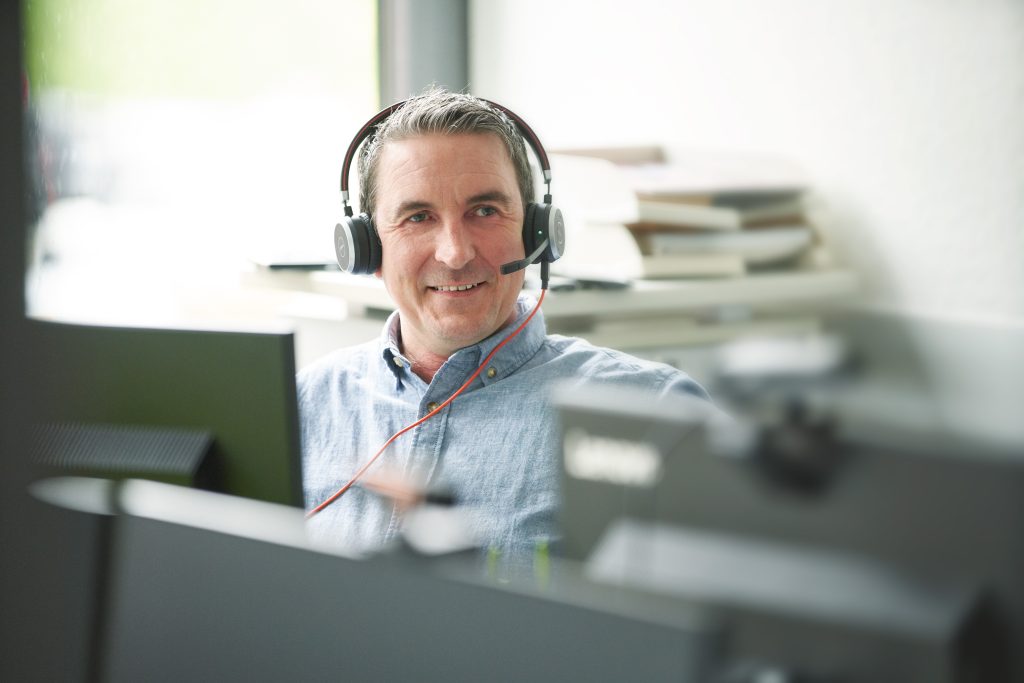tegosgroup Mitarbeiter am Schreibtisch mit Headset