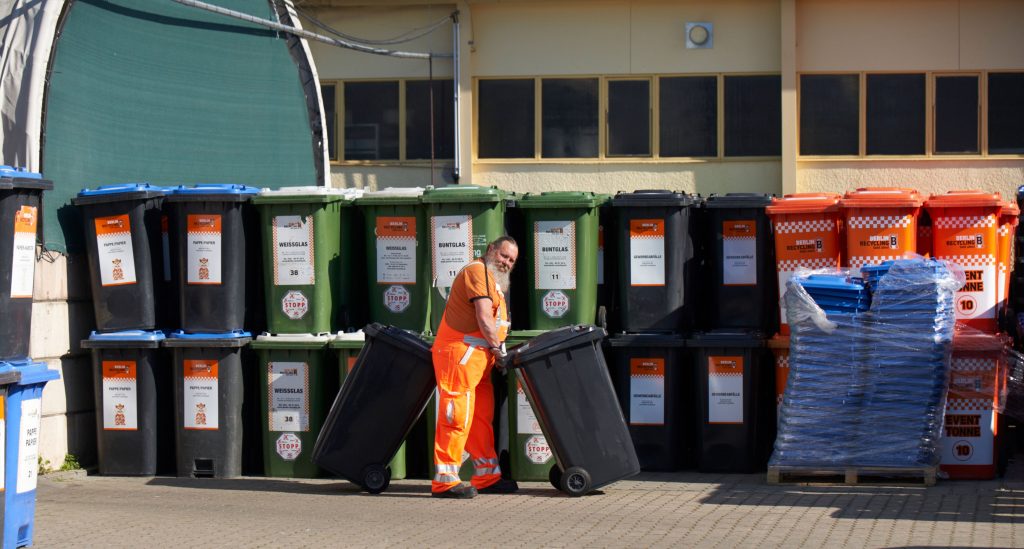 Recyclinghof Mitarbeiter mit Tonnen, lachend